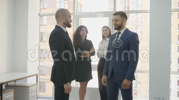 办公室工作人员两名年轻妇女和两名年轻男子两名男子互相交谈和握手两名妇女在视频的预览图