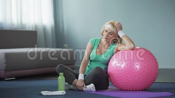 劳累的中年女性在积极的家庭锻炼后在瑜伽垫上放松呼吸困难视频的预览图