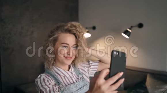 女孩用手机拍照在房子里微笑视频的预览图