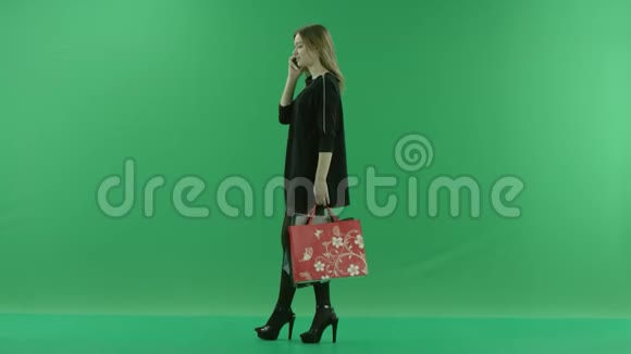 年轻有魅力的女士带着购物袋在手机上交谈颜色关键绿色背景视频的预览图