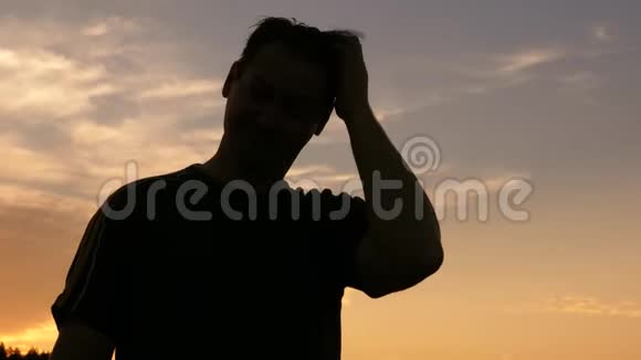 人在夕阳下挠头的剪影视频的预览图
