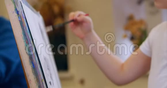 年轻的艺术家的手小女人艺术家用画笔描绘画布坐着一张桌子画在画布上流程视频的预览图