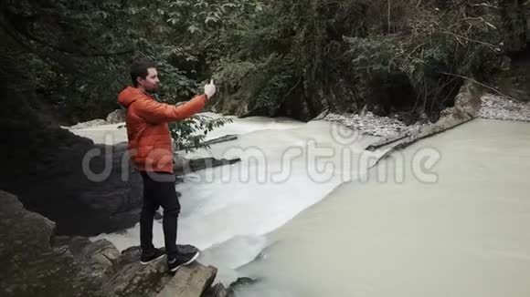 游客在秋日用智能手机拍摄一条山河和森林视频的预览图