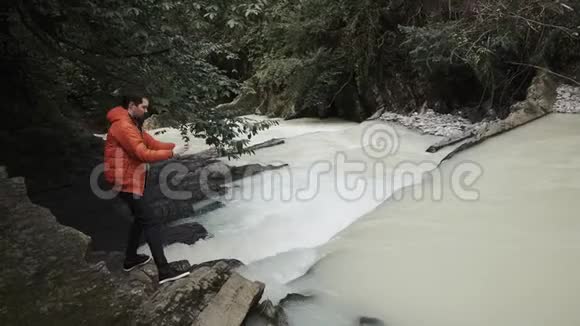 穿暖和衣服的年轻人在大自然中用手机拍照视频的预览图