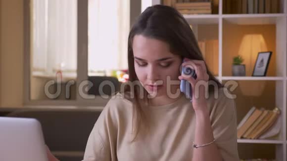 一位年轻迷人的高加索女商人的特写镜头她打了个电话在室内工作手提电脑视频的预览图