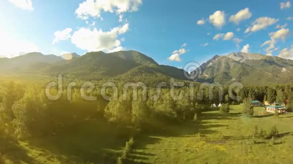 空中射击在草地和树木之上飞到山上去太阳耀斑视频的预览图
