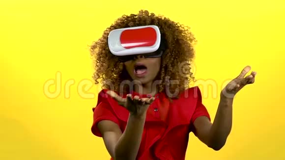 戴着虚拟现实眼镜的女孩正在看一段有趣的视频黄色背景慢动作视频的预览图