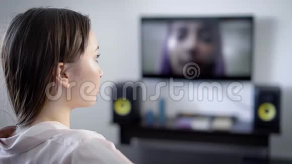 独自一人的女孩晚上坐在她家的客厅里看电视集中精力看电影情节视频的预览图