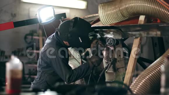 一家焊接厂的男工人戴着焊接面罩正在从事金属建筑在工业工厂焊接视频的预览图