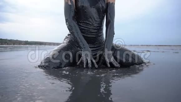 可爱的滑头金发坐着被黑泥浸湿看起来像石油视频的预览图