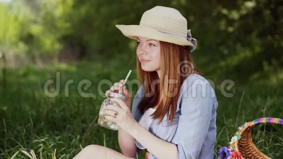 戴帽子的微笑女孩享受大自然的冰柠檬水视频的预览图