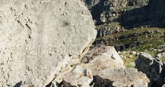 一位老妇人用手机在岩石上点击图片视频的预览图