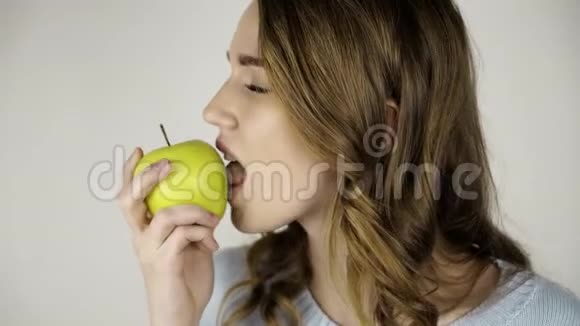 漂亮的头发女人咬着一个绿色的苹果舔着嘴唇视频的预览图