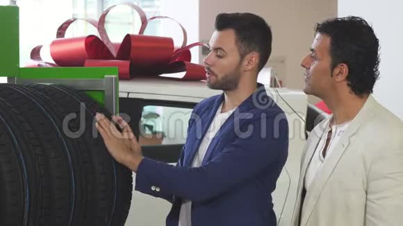 年轻的推销员帮助成熟的顾客选择汽车轮胎视频的预览图
