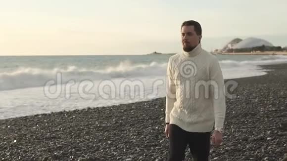 秋天穿暖和毛衣的成年男子漫步在海滩上视频的预览图