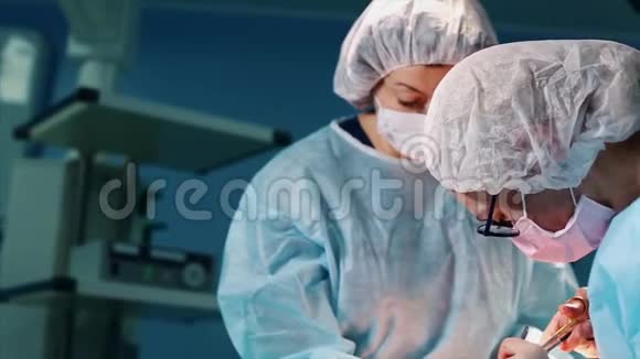 专业外科医生和助手在手术过程中讨论手术他们在现代化的医院手术室工作视频的预览图