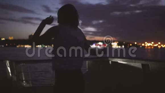 一个年轻快乐的女孩的剪影感觉很棒在黑暗的夜晚在船上跳舞女人很开心视频的预览图