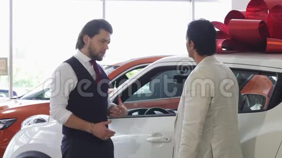 专业汽车推销员为他的男性顾客打开一扇汽车的门视频的预览图