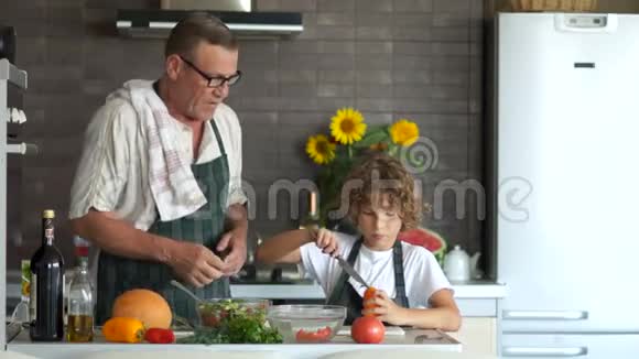 那个小学生把甜椒切成了色拉他的祖父站在他旁边把沙拉搅在碗里适当视频的预览图