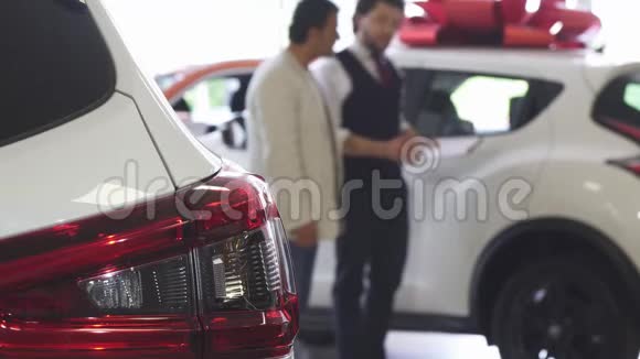 专业汽车销售人员向他的男性顾客展示汽车视频的预览图