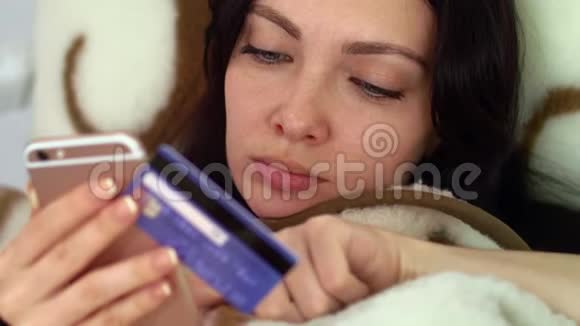 一个女人正在床上用信用卡买东西视频的预览图