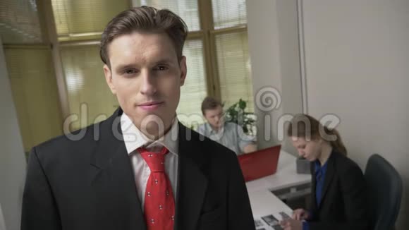 穿西装的年轻人正微笑着看着摄像机一个男人和一个女孩在办公室工作视频的预览图