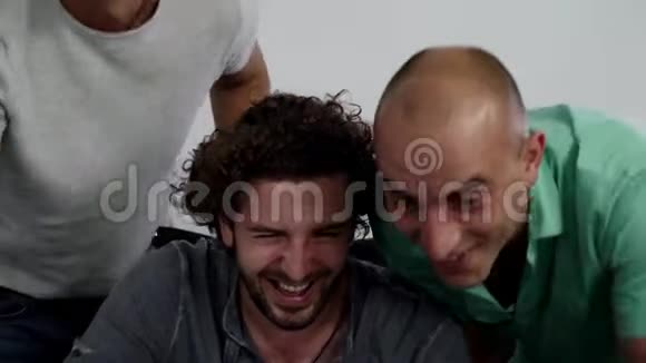 三个年轻英俊的男人正看着笔记本电脑高兴地笑在一起视频的预览图
