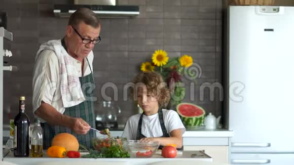 爷爷和孙子一起准备晚餐这个男孩正在切甜胡椒做沙拉一个男人送沙拉视频的预览图