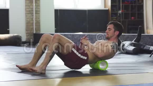 运动肌肉男子训练后放松使用泡沫滚筒视频的预览图