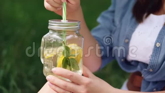 戴帽子的微笑女孩享受大自然的冰柠檬水视频的预览图