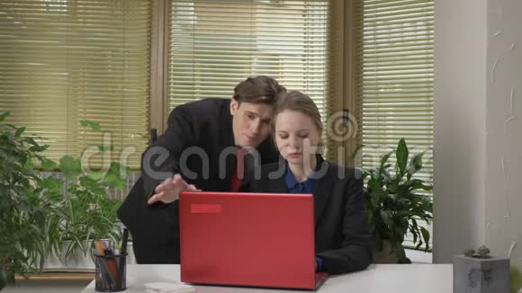 穿西装的年轻人和他的雇员调情试图关闭她的笔记本电脑女孩不同意办公室的工作视频的预览图