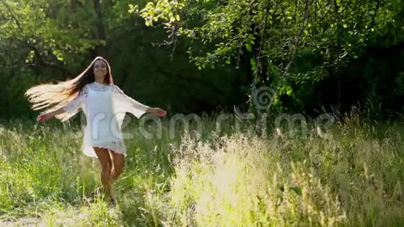 可爱的黑发女孩在公园里穿着白色连衣裙旋转视频的预览图