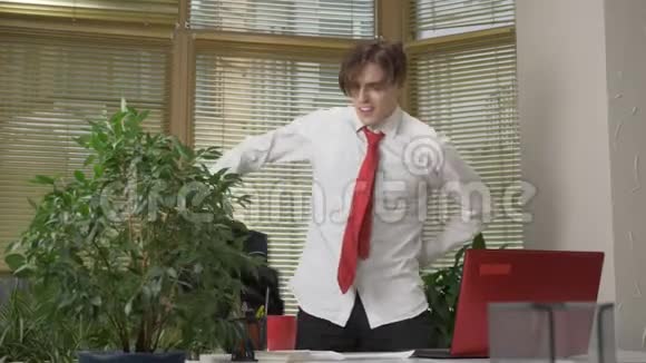 穿西装的年轻人在办公室跳舞脱下夹克做滑稽的脸周围的傻瓜快乐工作领域视频的预览图