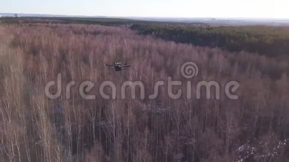 无人机无人驾驶飞机在天空中翱翔在枯萎的森林和城市的背景上剪辑重型升降机视频的预览图