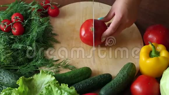 一位女厨师的特写在木制砧板上切下一个成熟的番茄视频的预览图