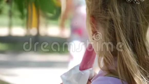 小女孩在炎热的夏天在公园的操场吃冰淇淋视频的预览图