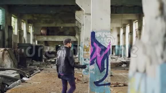 男性涂鸦画家正在用废弃的空楼内的喷漆创造抽象的形象旧的柱子在视频的预览图