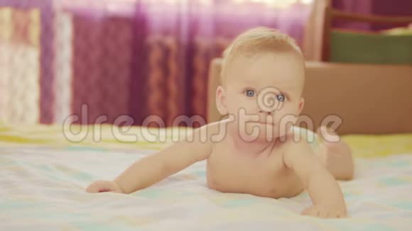 一个漂亮的婴儿躺在他的肚子上看着相机微笑视频的预览图