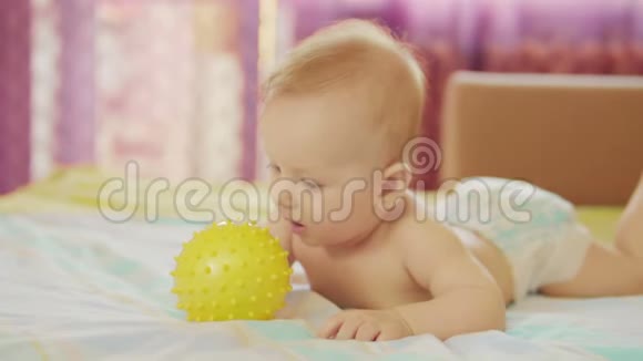 一个美丽的婴儿躺着他手里拿着球玩它视频的预览图
