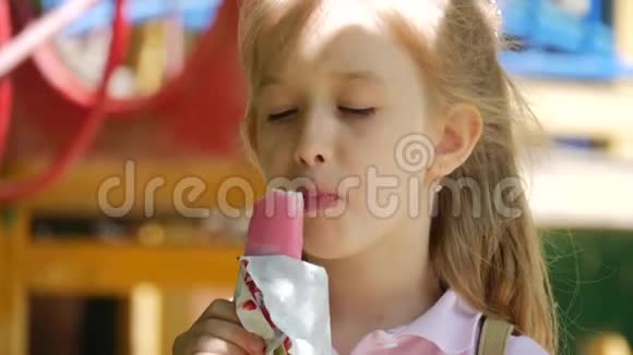 小女孩在炎热的夏天在公园的操场吃冰淇淋视频的预览图