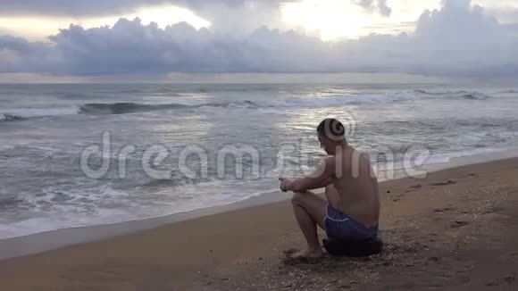 日落时分带着手机在热带海洋海滩上的年轻人视频的预览图