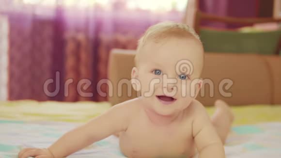 一个漂亮的婴儿躺在他的肚子上看着相机微笑视频的预览图