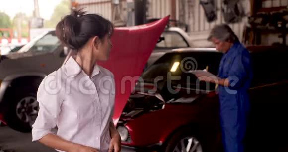 愤怒的顾客的肖像而一个机械师在后台的汽车上工作视频的预览图