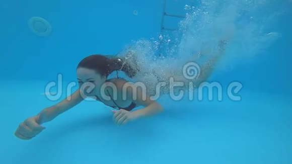 在干净的游泳池里的女人表现出手势张开眼睛在水下游泳视频的预览图