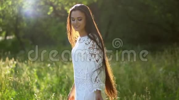 可爱的黑发女孩在公园里穿着白色连衣裙旋转视频的预览图