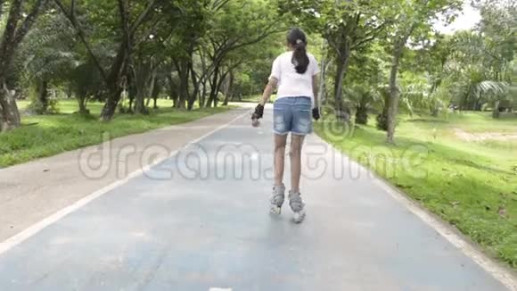 亚洲可爱的女孩在公共公园的路上玩滚轮刀视频的预览图