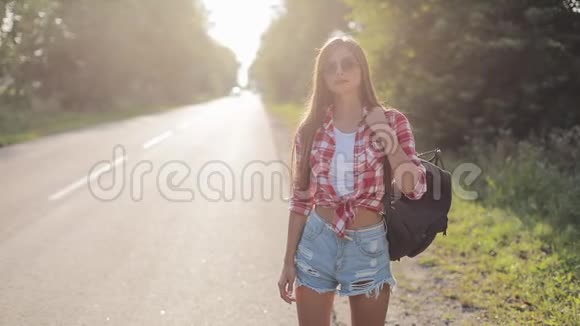 旅行者年轻的女人在阳光明媚的路上搭便车年轻女孩想搭车开始一段旅程夏季视频的预览图
