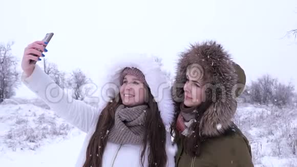 快乐女朋友在雪地背景下在智能手机上拍照视频的预览图