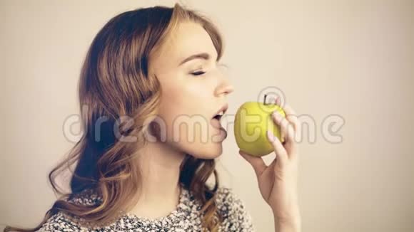 浅头发的女人咬着一个绿色的苹果看着镜头调色视频的预览图