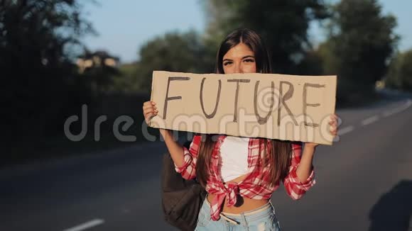 年轻漂亮的女人搭车站在路上举着未来的标志夏季视频的预览图